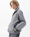 A person with short, wavy blond hair wears the Rag & Bone carrie reversible jacket and blue jeans, standing against a plain white background and looking toward the camera.