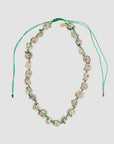 The Clare Vivier Checker Shell Necklace features small, patterned seashells strung on a green cord with an adjustable pulley closure and two loose ends.