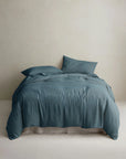 Teal linen duvet cover and pillows by Cultiver Goods on bed, set against a light wall in a serene bedroom setting.