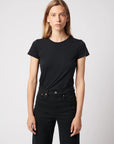 A person with long, straight blonde hair wears the Majestic Filatures Deluxe Cotton S/S Crewneck in black and black pants, standing against a light gray background and looking directly at the camera with a neutral expression.