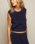 A woman with wavy blonde hair wears the Perfectwhitetee ELLIE terry banded tank and matching navy blue pants, standing against a light background and gazing to the side with a relaxed look.