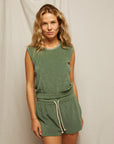 A woman with wavy blond hair wears the Perfectwhitetee ELLIE terry banded tank and matching drawstring shorts, both in green, standing before a plain light-colored backdrop.