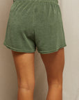 A person stands with their back to the camera, wearing Perfectwhitetee Summer Loop Terry Sweat Shorts in green with an elastic waistband against a neutral background.