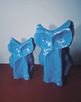 Pair of blue Serax Owl vases on a reddish-brown surface, minimal backdrop, Bungalow Furniture & Accessories.