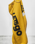 A yellow Circa '99 OG Sweat by Free City (sparrow, LLC) hangs on a white hook. Bold black "LET'S GO" and a small white heart are featured, with the art+commerce logo and FREECITYLARGE detail beneath. Medium weight polyblend.