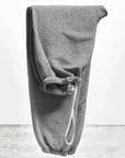 A pair of BASIC GOODNESS OG SWEATPANTS by Free City (sparrow, LLC) in gray French terry with an elastic waistband and white drawstring, neatly folded upright on a light gray textured surface against a plain white background.
