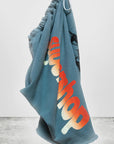 A blue bag of soft French terry, inspired by Free City (sparrow, LLC)'s Sparrow Homestud Yumm Cutoffs, hangs on display. It features bold orange-to-yellow "supershop" lettering and "freecitysupershop" at the bottom.