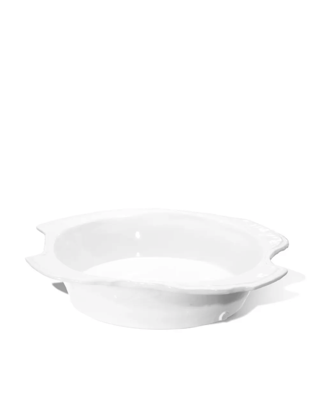 A white ceramic pie dish with fluted edges, displayed on a plain white background, emphasizing its simple and elegant bungalow-inspired design by Montes Doggett.