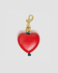The Clare Vivier Grande Heart Fob in Poppy is a vintage gold-plated keychain with a smooth, shiny red heart-shaped charm, shown against a plain white background.