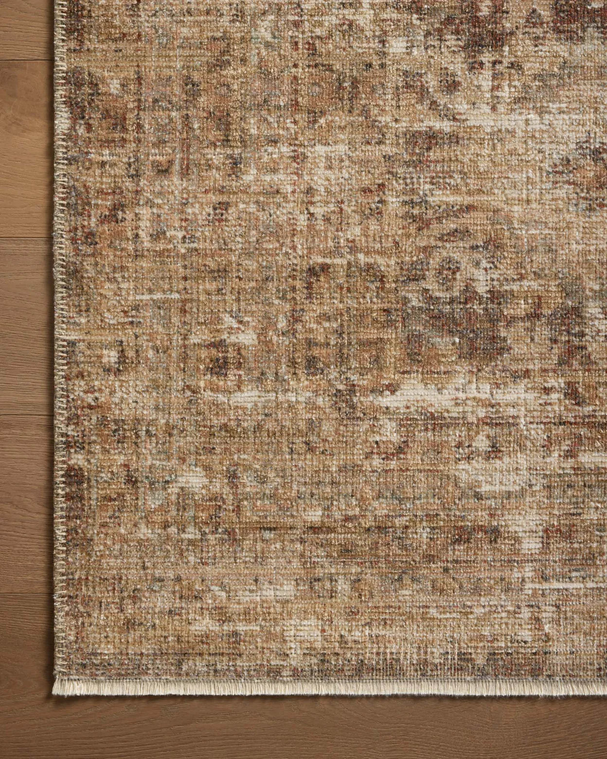 A close-up view of a Loloi Rugs Bark / Multi Rug with a varied brown, beige, and white distressed pattern in Arizona style, laid out on a wooden floor.