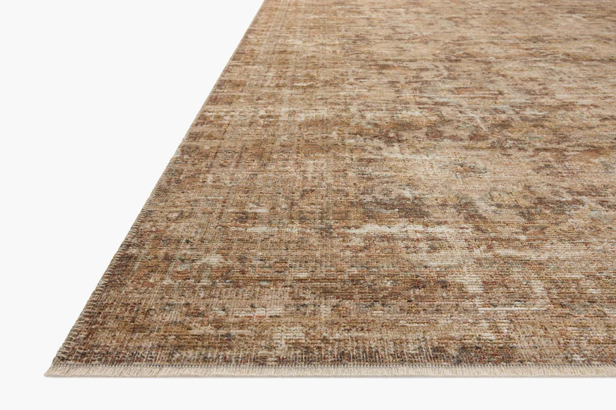 A close-up image of a Bark / Multi Rug from Loloi Rugs with a subtle, distressed pattern in shades of brown and beige, viewed from a low angle to highlight its thin profile and Bungalow style.