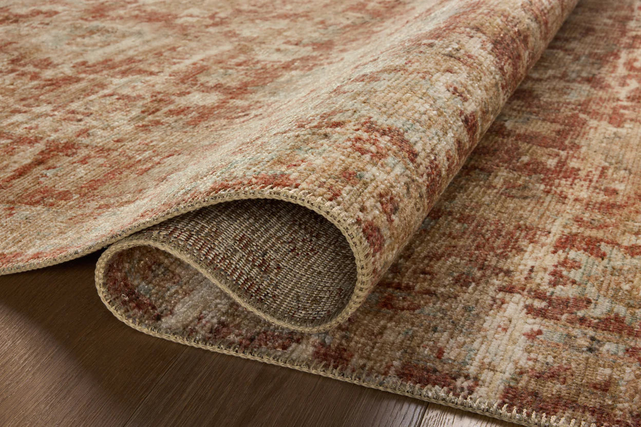 Close-up of a partially rolled, textured Loloi Rugs Brick / Multi Rug displaying earthy tones and intricate patterns on a wooden floor in a Scottsdale Arizona bungalow.
