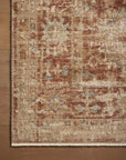 A detailed, ornate Loloi Rugs area rug with a Brick / Multi pattern featuring shades of brown, red, and beige, laid out on the wooden floor of a Scottsdale Arizona bungalow, partially covering it.
