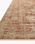A close-up of a part of a light brown Loloi Rugs Brick / Multi Rug with faded red and blue patterns, on a white background. The edge of the rug is slightly curled in a Scottsdale Arizona bungalow.