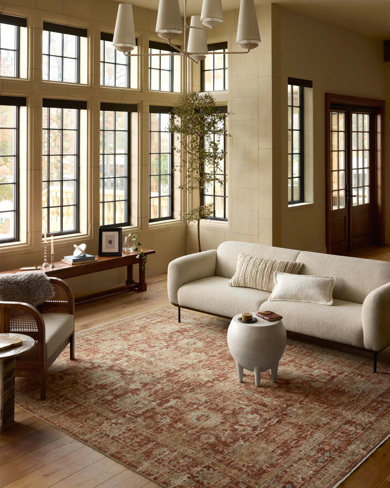 Elegant bungalow living room featuring large windows, a beige sofa, a unique round coffee table, and a Loloi Rugs Brick / Multi Rug, accented by calm, natural lighting and neutral walls in Scottsdale Arizona.