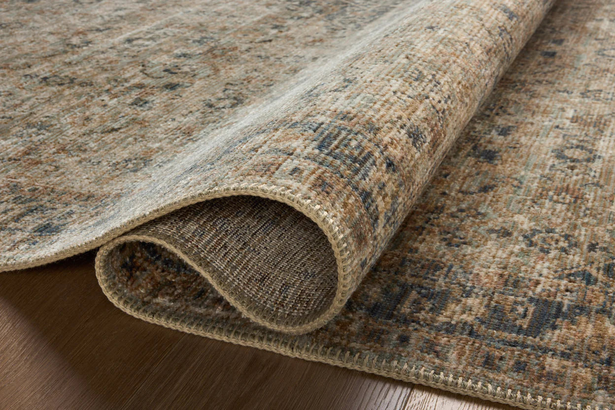 A close-up of a rolled-up Sage / Navy rug by Loloi Rugs in a Scottsdale Arizona bungalow, highlighting its texture and intricate design.