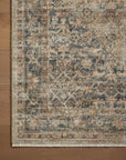 A close-up view of a Sage / Navy Rug by Loloi Rugs with a detailed, vintage-style pattern in muted shades of blues, browns, and creams, displayed on a wooden floor in a Scottsdale Arizona bungalow.