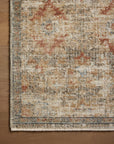 A close-up view of a textured Loloi Rugs Grey / Sunset Rug with a vintage, distressed design featuring patterns in shades of beige, blue, and red, with fringe detailing on the edge in a Scottsdale Arizona bungalow.
