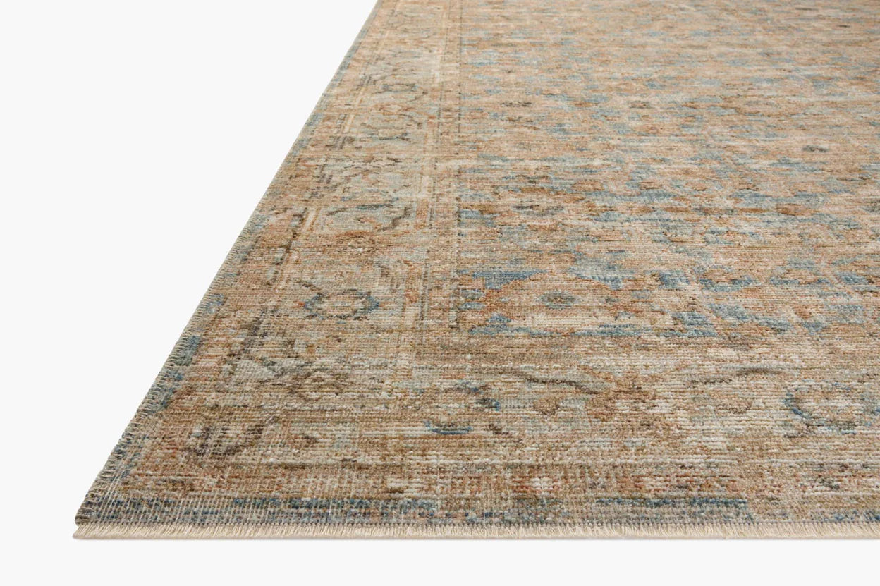 Close-up of a section of a Ocean / Sand Rug with a subtle, faded floral pattern in muted blue and beige tones, typical of a Scottsdale, Arizona bungalow, showing detail of the weave and edges by Loloi Rugs.