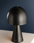 The Hudson Valley Hopkins Rechargeable is a modern, matte black dimmable accent lamp with a dome-shaped mushroom silhouette and conical base, displayed on a white surface against a dark blue background.
