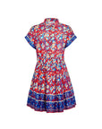 The Howard Dress by Hunter Bell NYC is a short-sleeved, collared button-up featuring a vibrant Tapestry Floral print, flared skirt with blue borders on the hem and sleeves, and an elastic waist for comfort.