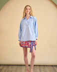 Evangeline shirt by Hunter Bell NYC styled with a floral wrap skirt against a neutral beige background.