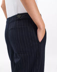 A person wearing Rag & Bone irina ponte tailored pants, shown waist down with one hand in a side pocket, displaying the dark navy wide-leg design with pinstripes and back pocket against a plain white background.