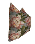The Rennah Collective Iris Pillow 22x22 features a floral design with large pink and white flowers and green leaves on a muted gray polyester-linen cover, shown upright against a white background.
