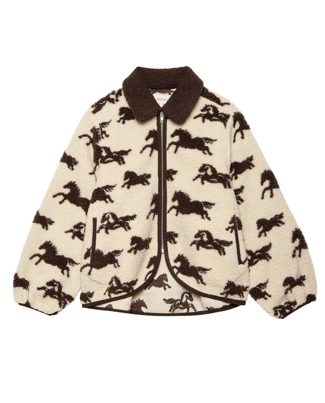 The Pasture Jacket by The Great Inc. is a cream sherpa teddy jacket with a brown collar, all-over galloping horse motif, front zipper, relaxed fit, and elastic cuffs.