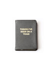 A Mini Notebook by Kempton & Co. in black goatskin leather features gold-embossed "THINGS I'VE SEEN ON A TRAIN" on the cover and lined pages inside, shown centered on a plain white background.