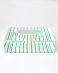 The Le Sunshine Stripe Decorative Bowl 7x7x2 by Kerri Rosenthal features green vertical stripes, blue wavy lines, and a central circular cutout. Elegantly placed on a reflective white surface, it's perfect for any coffee table setting.