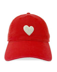 The Kerri Rosenthal Baseball Hat Heart Patch is a red cap with a white embroidered heart on the front, blending popular styles for a fresh look, pictured against a plain white background.