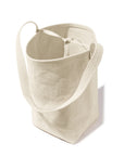 The Uma by Kule is a beige cotton canvas tote bag with long handles, shown standing upright against a white background. Its interior displays an unlined, natural fabric texture that highlights its minimalist design.