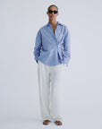 Love Stories HILLARY striped shirt styled with white pants and sandals, relaxed modern look against soft background.