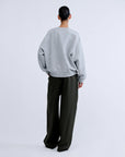 SLOANE Love Stories sweater in dark, relaxed fit, styled with loose pants; minimalist neutral background.