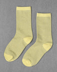 Unified Glitter Socks in light yellow with a subtle shimmer, displayed flat on a gray textured surface.