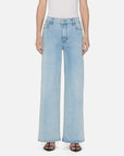 A person is wearing FRAME's Le Slim Palazzo light blue wide-leg jeans, crafted from sustainable cotton in a chic palazzo silhouette with a high rise and two front pockets. They wear a white sleeveless top and black open-toe sandals against a white background.