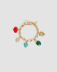 The LE Heartbreaker Bracelet by Clare Vivier features a gold-plated brass chain and five charming pendants—a red apple, gold heart, white pearl cluster, turquoise heart, and green heart—displayed on a plain light background.