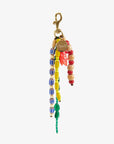 The Clare Vivier Le Long Beaded Tassel is a colorful keychain with strands of blue, yellow, red, wood, and green beads, a small red animal charm, and a vintage gold-plated clip with a circular gold tag.