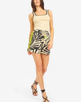A woman in a beige square-neck tank, Le Superbe BoHo Rhapsody Beach Boxer in black and beige zebra print with a drawstring, and black strappy sandals poses confidently against a plain white background.
