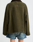 A person wearing the Denimist O/S Field Jacket in sturdy cotton with a dark collar and frayed blue denim shorts, shown from the back against a plain light background.