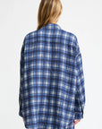 A person with long, light brown hair stands facing away from the camera, wearing the Denimist BUTTON FRONT SHIRT in blue/ecru plaid against a plain white background.