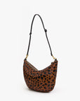 The Clare Vivier F25-Lune is a brown hair-on leather shoulder bag with a black leopard print, adjustable black strap, and gold hardware, shown against a white background.