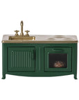 The Maileg Furniture kitchen set by Maileg is a miniature green set with a gold sink, faucet, stovetop, and oven. Its vintage-inspired design and tiny food in the oven make it ideal for any dollhouse or Maileg Mouse collection.
