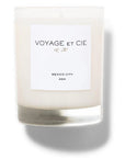 A white soy coconut blend candle from Voyage Et Cie, 14 OZ Classic Highball, sits in a clear glass jar labeled “VOYAGE ET CIE est. 2005, MEXICO CITY, ASH,” casting a soft shadow on a white background.