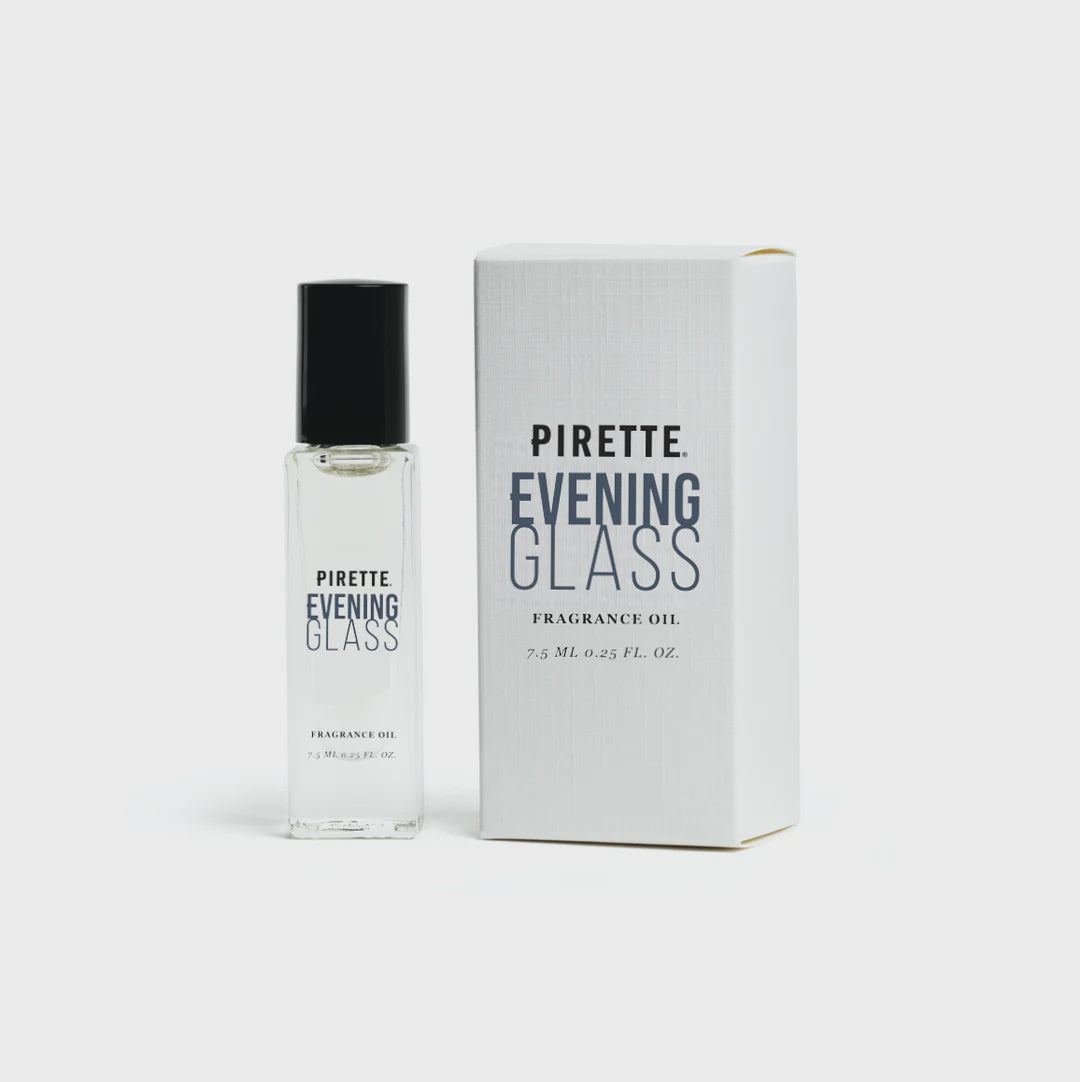 A clear glass bottle of Pirette Mini Fragrance Oil with a rollerball applicator next to its white box packaging, presented against a plain white background.