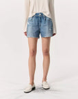 A person wearing a striped long-sleeve shirt, Miramar Walking Short by Rag & Bone with an elastic waistband and denim print, and white loafers stands against a neutral background. Their hands are not visible.