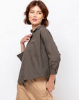 Monday12 Zoe Shirt in Dark Olive styled with beige pants, casual look, model gazing sideways, hand at collar.