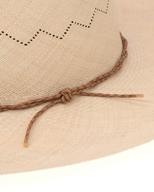 Close-up of a beige Ninakuru Luna hat featuring decorative perforations and a braided leather band tied in a knot. The texture of the hat is detailed and tactile.
