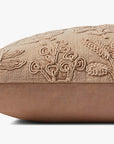 The PMH0054 Louise Natural Pillow 12x27 by Loloi Rugs is a rectangular beige linen pillow featuring textured, embroidered botanical patterns, displayed from the side against a white background.